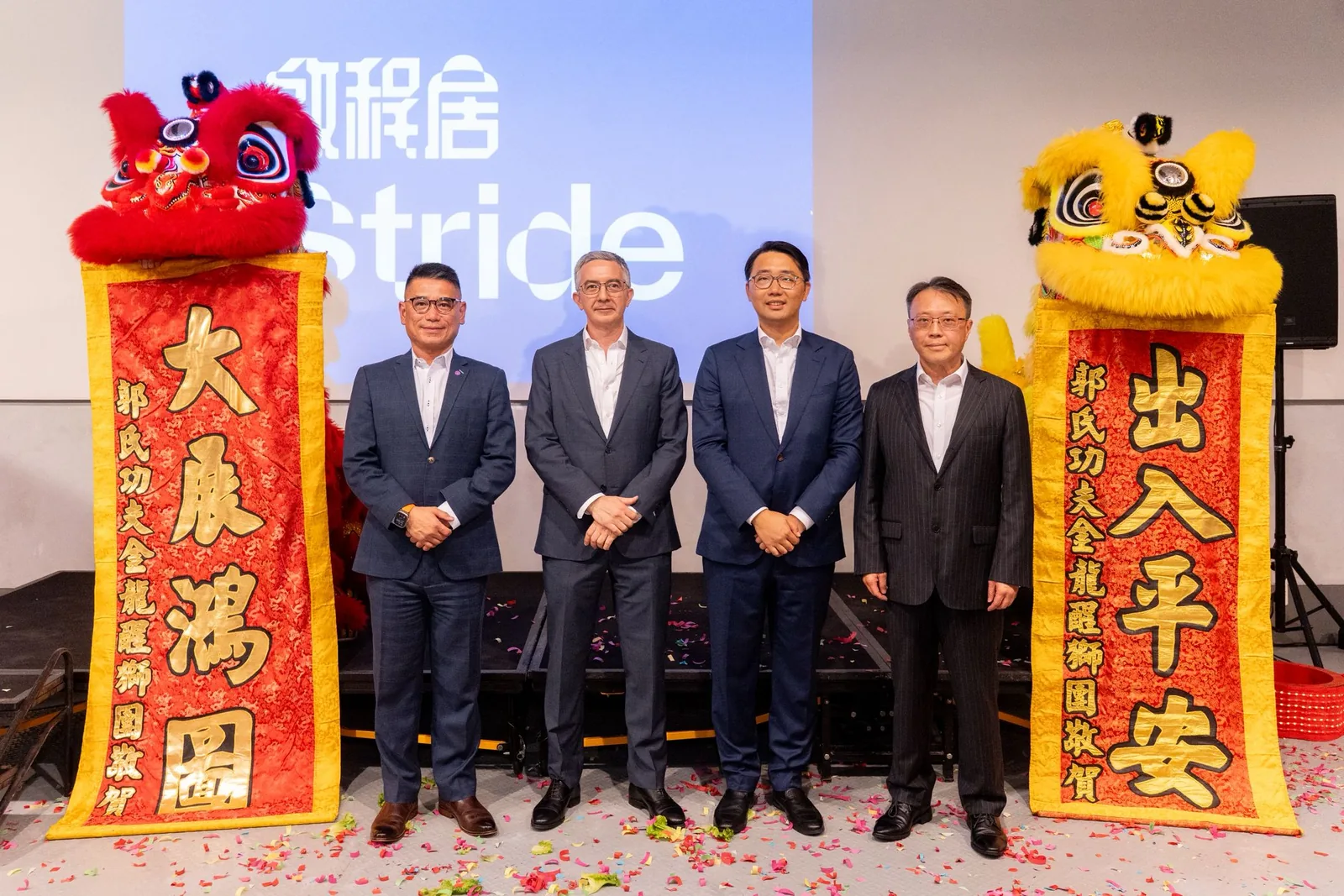 Stride executives on stage at the official opening of Stride Wong Chuk Hang, flanked by lion dance lions and celebratory scrolls, Hong Kong, 18 August 2026