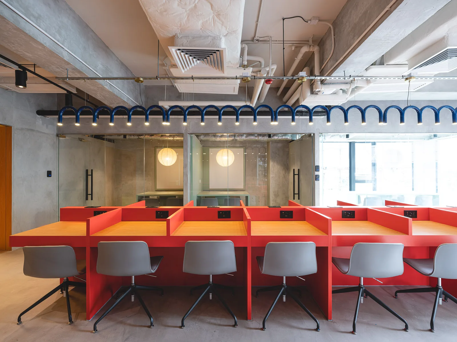 Study room at Stride Wong Chuk Hang with red study carrels, oak desktops and glazed meeting rooms